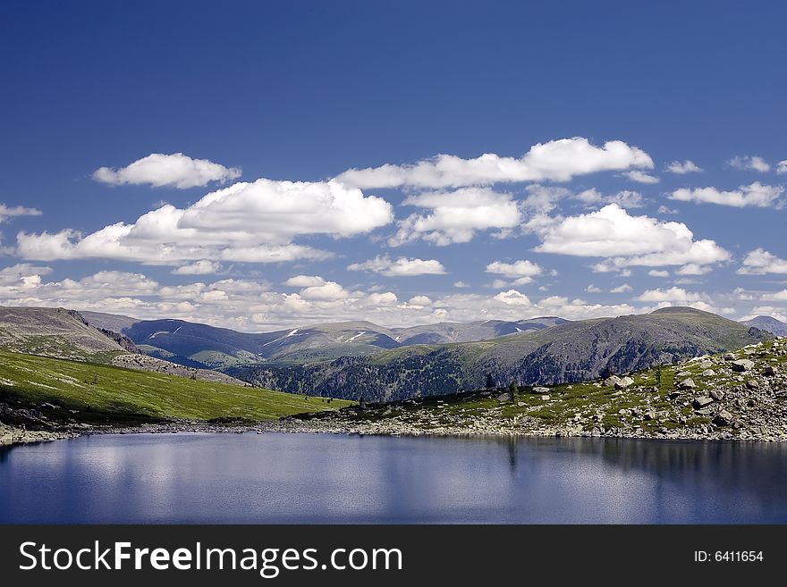 Lake in high mountains of Altai, summer, blue sky and white clouds