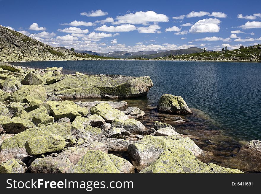 Lake in high mountains of Altai, summer, blue sky and white clouds