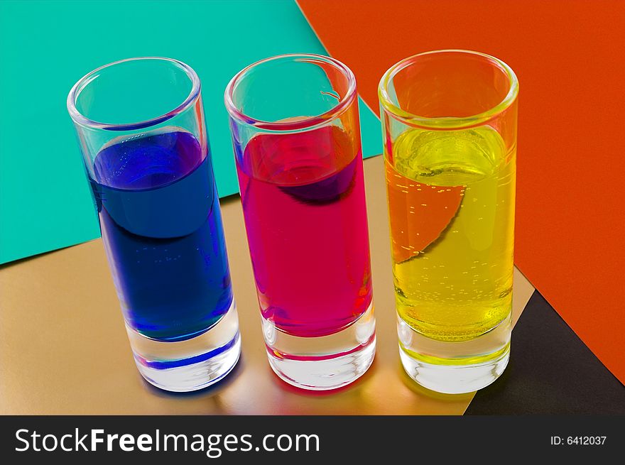 Three glasses with colorful liquid on a color background. Three glasses with colorful liquid on a color background
