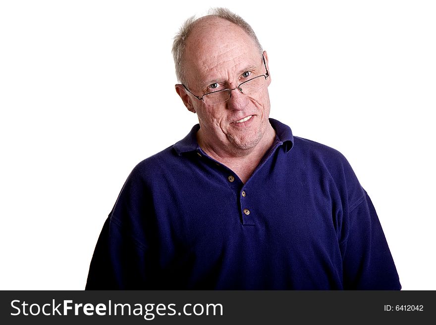 An older bald guy smiling over his reading glasses in a blue shirt on a white background. An older bald guy smiling over his reading glasses in a blue shirt on a white background