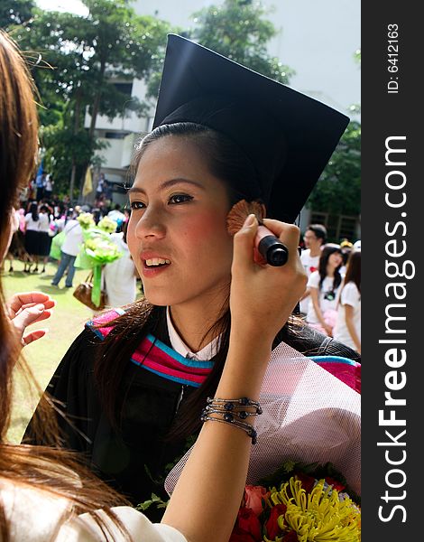 Beautiful young Asian graduate having her make-up done for graduation day.