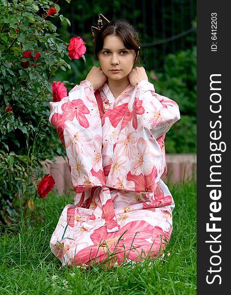 Girl in a pink yukata near rosebush. Girl in a pink yukata near rosebush