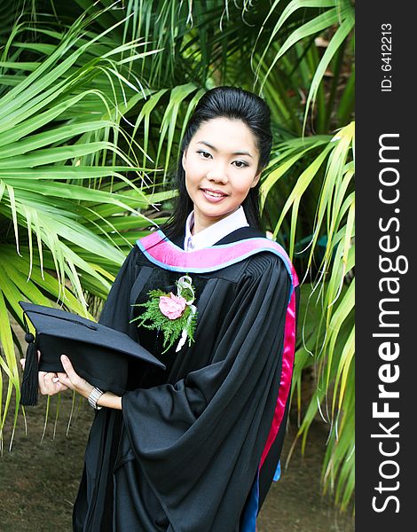 Beautiful young Asian graduate in robes on graduation day.