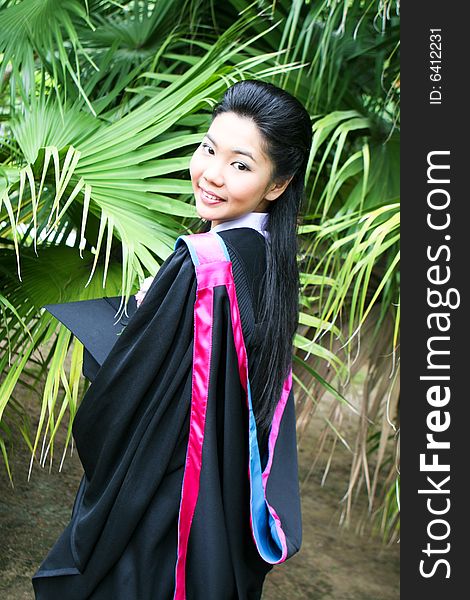 Beautiful young Asian graduate in robes on graduation day.