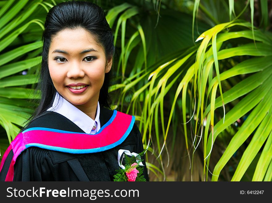 Beautiful young Asian graduate in robes on graduation day.