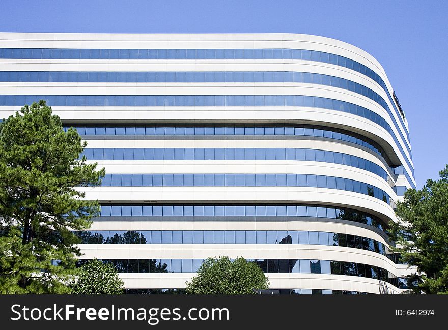 A modern concrete and glass building curving against a blue sky