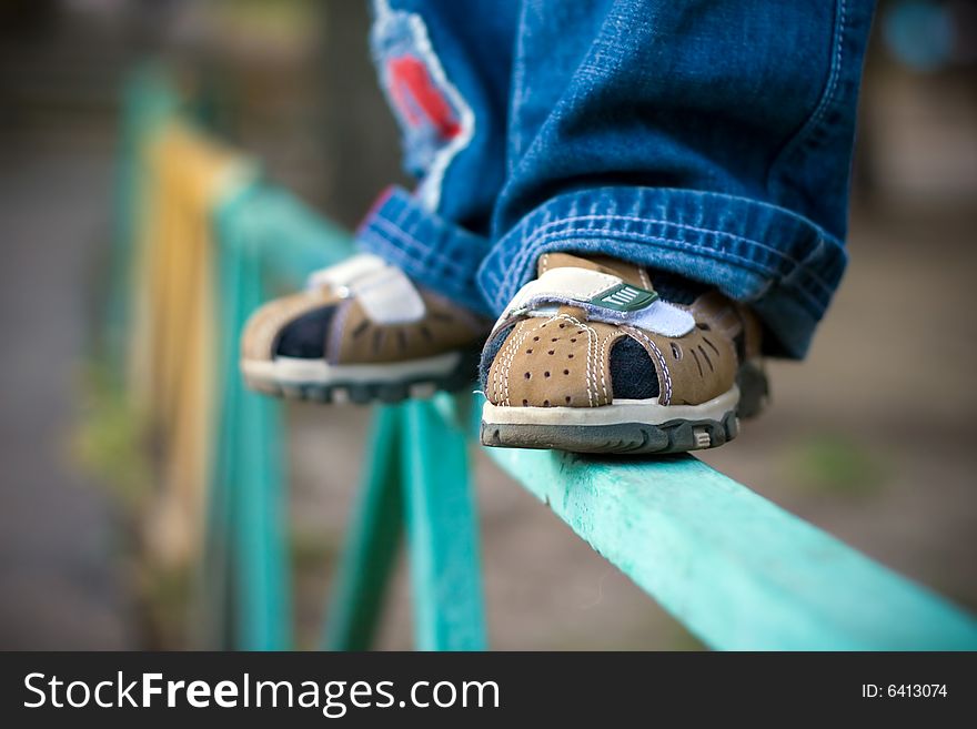 Legs of the child worth on a fence