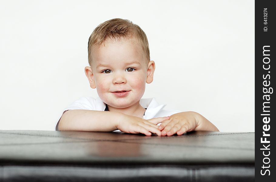A young baby is posing for the camera in a studio.  Horizontally framed shot. A young baby is posing for the camera in a studio.  Horizontally framed shot.