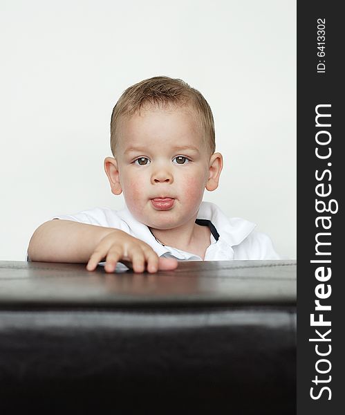 A young baby is posing for the camera in a studio.  Vertically framed shot. A young baby is posing for the camera in a studio.  Vertically framed shot.