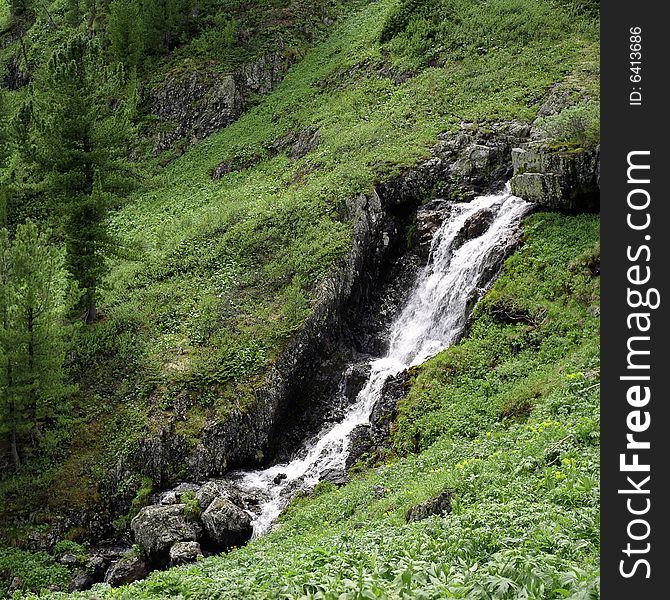 River flow in high mountains, green grass, water and clouds