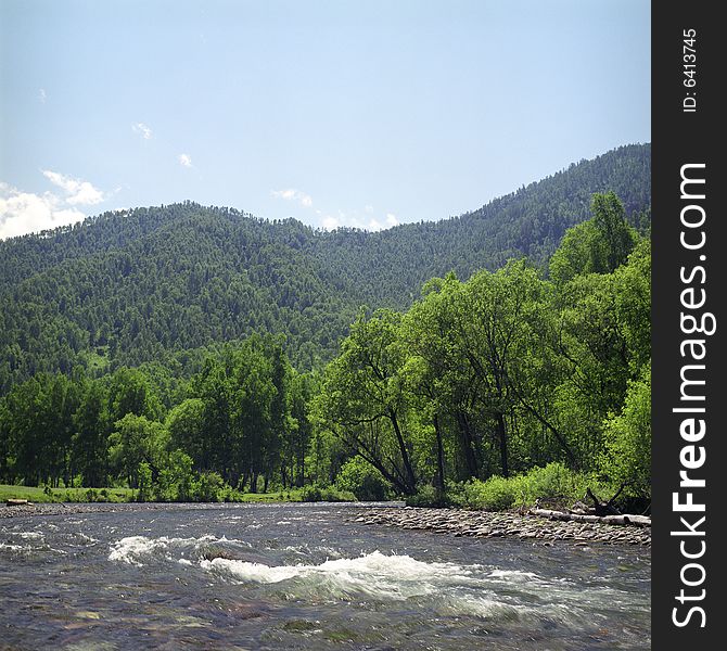 River flow in high mountains, green grass, water and clouds