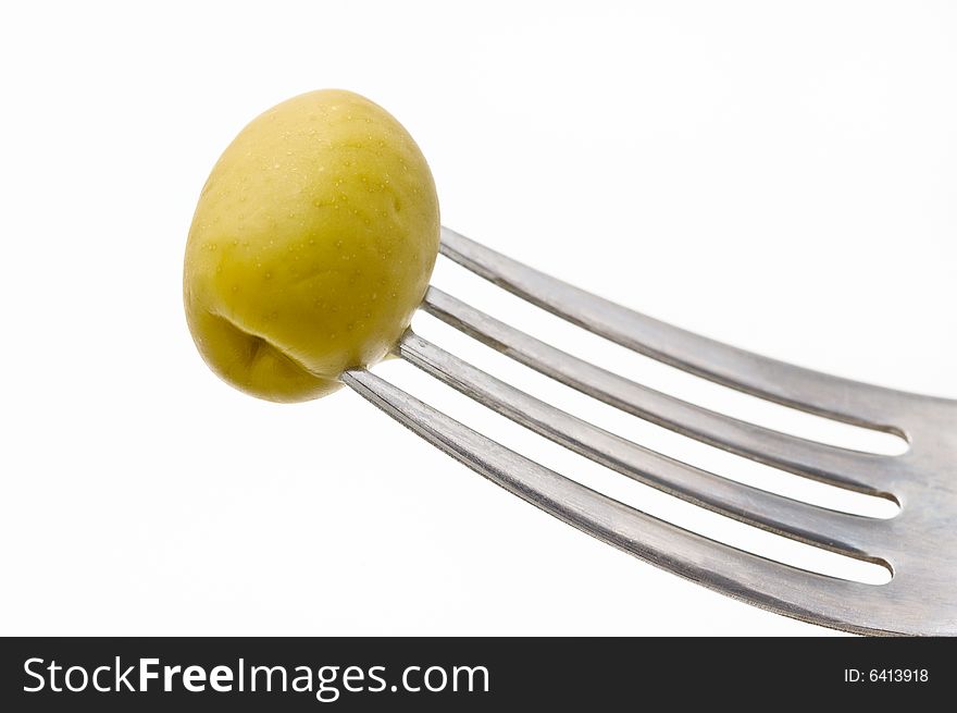 Fresh green olive in a fork, white background.
