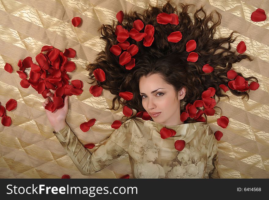 Beautiful woman with red rose petals on golden background. Beautiful woman with red rose petals on golden background