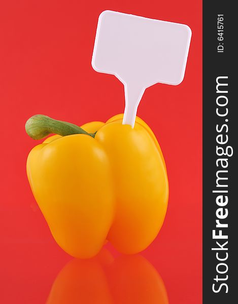 Yellow paprika against red background with price tag