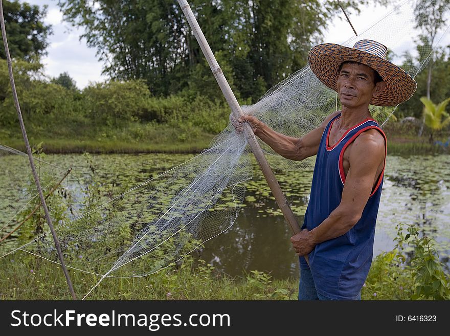 Fisherman with stave, Asia, in Thailand at a small lake