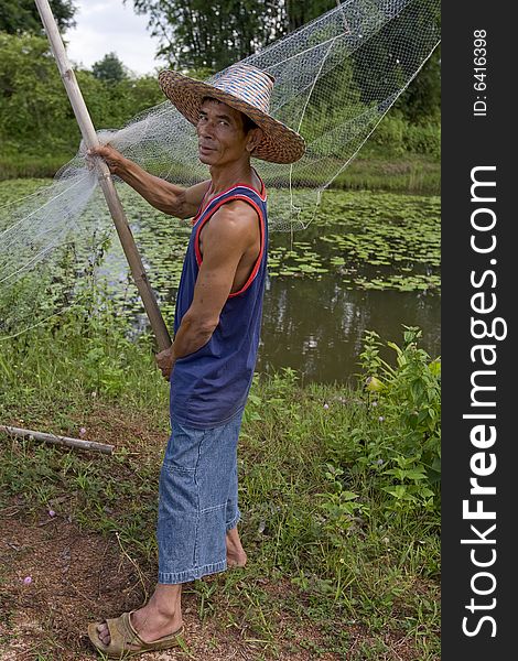 Fisherman with stave, Asia, in Thailand at a small lake