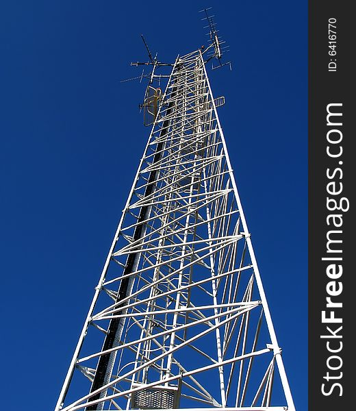 Tall white cellphone tower with blue sky