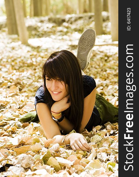 Young woman laying over fallen leaves. Young woman laying over fallen leaves.