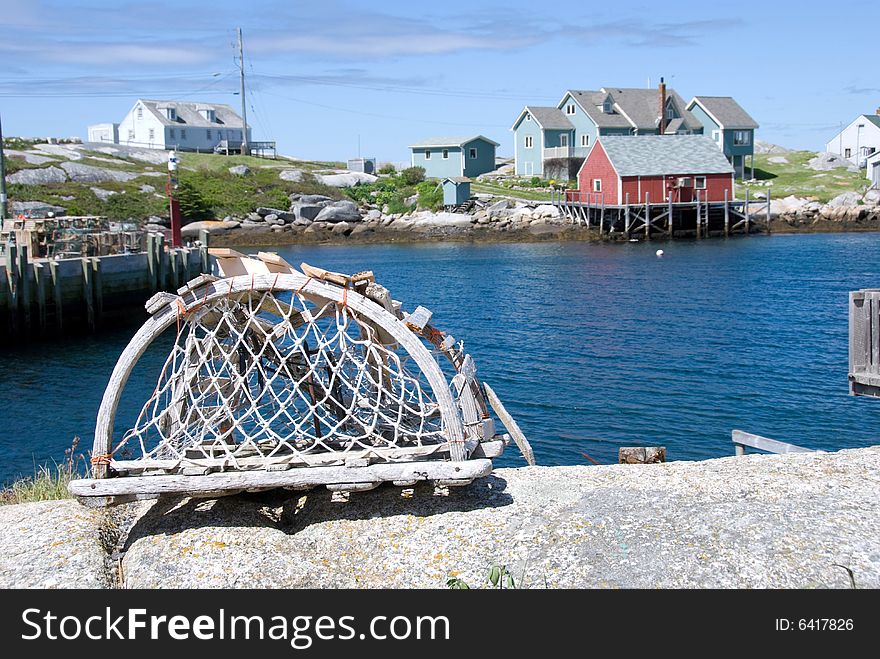 A view of Peggy's Cove, accented with a lobster trap in the foreground. Located in Nova Scotia, Canada