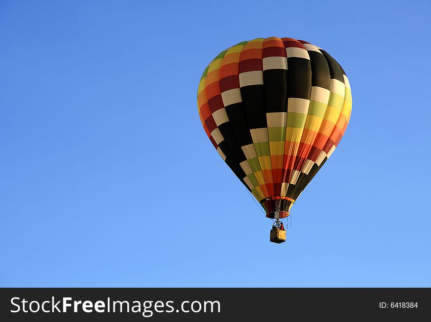 Multicoloured hot air balloon in the blue sky.
