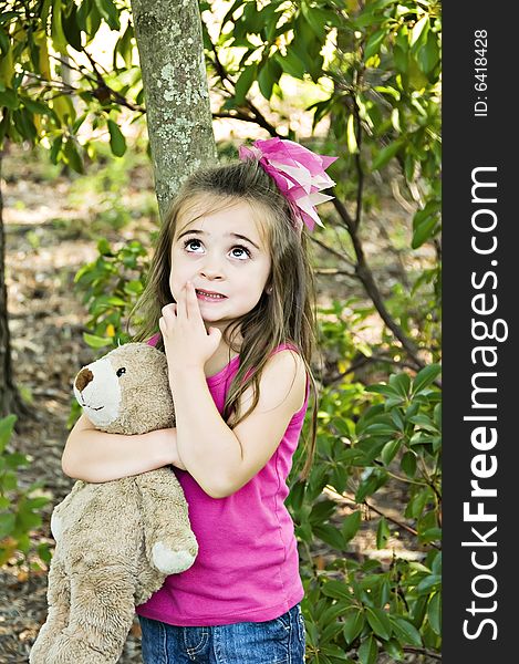 Little girl looking up with her hand next to her mouth, thinking and holding her best friend, her teddy bear. Little girl looking up with her hand next to her mouth, thinking and holding her best friend, her teddy bear.
