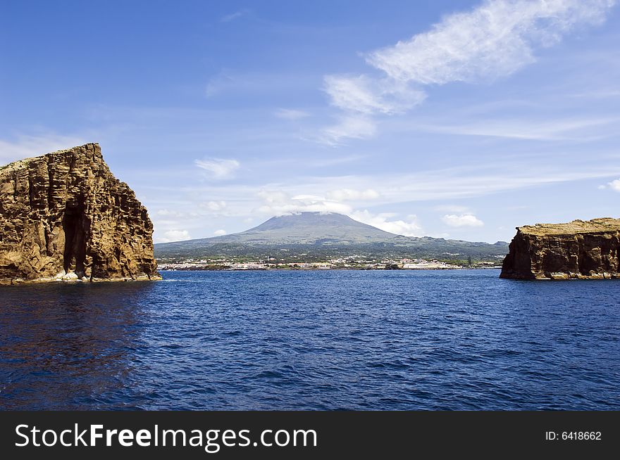 View from the sea of Pico Island, the volcano and the village of Madalena between two islets. View from the sea of Pico Island, the volcano and the village of Madalena between two islets