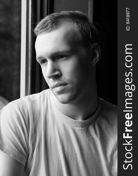 Natural light portrait of man in t-shirt at a window. Natural light portrait of man in t-shirt at a window