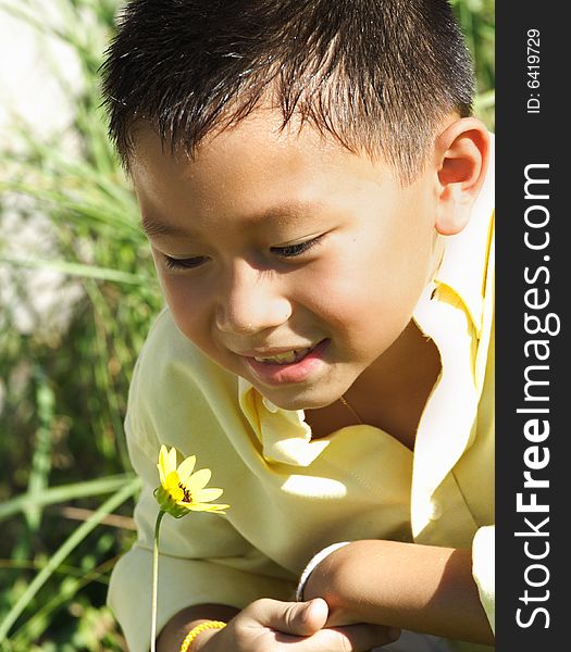 Young Boy Sniffing A Flower