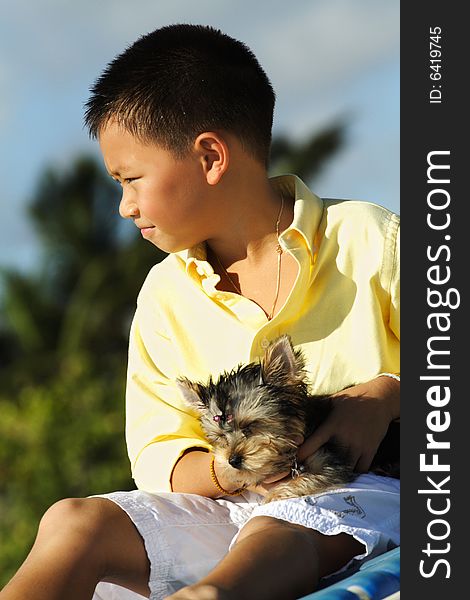 Young boy at the beach holding his baby yorkie. Young boy at the beach holding his baby yorkie