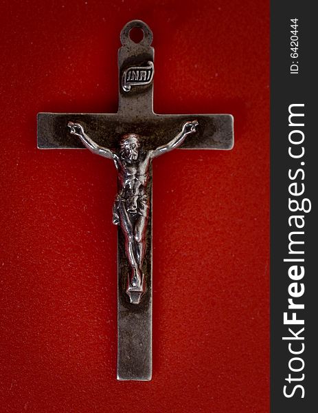 A close up macro shot of a crucifix set against red background. A close up macro shot of a crucifix set against red background