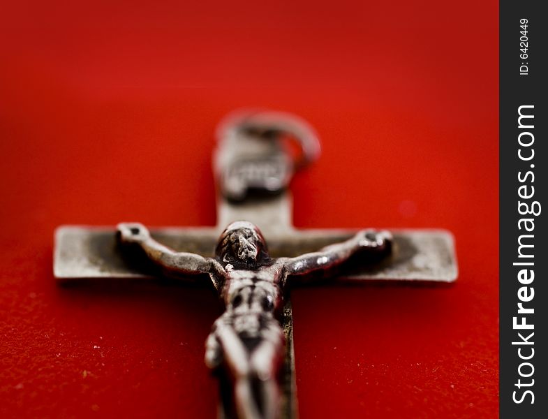 A close up macro shot of a crucifix set against red background