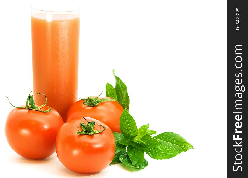 Fresh tomatoes with basilico herb and glass of tomato juice over white