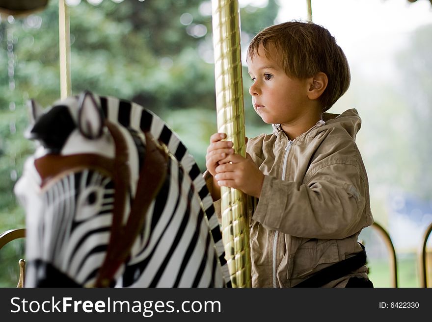 Little beauty boy on merry-go-round (on black-white zebra)