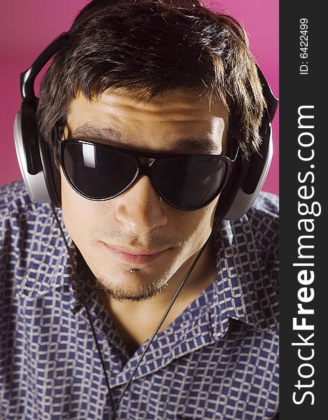 Young guy listening music with headphones, pink background. Young guy listening music with headphones, pink background.