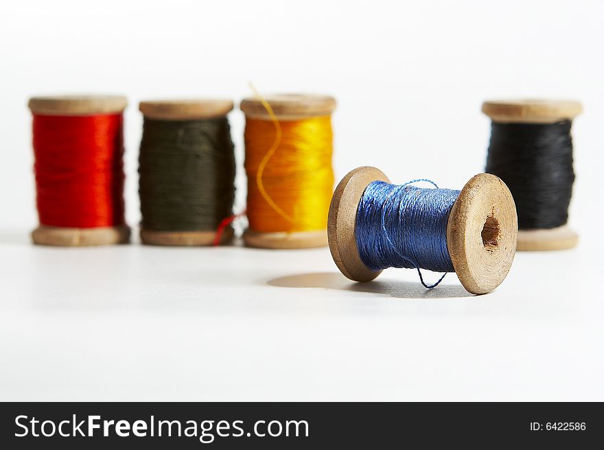 Group of 5 color spools of thread on white background