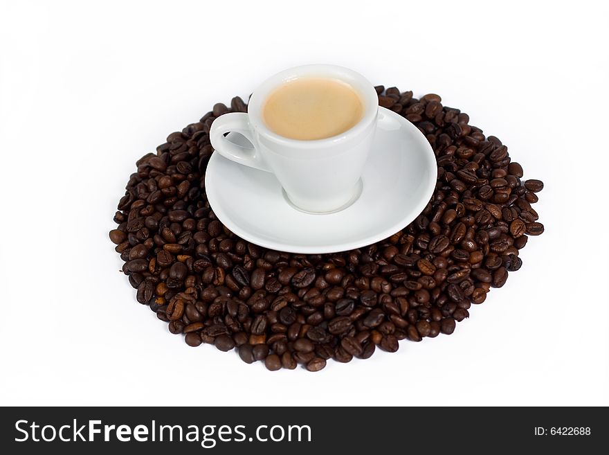 A cup of coffee on top of coffee beans isolated on white