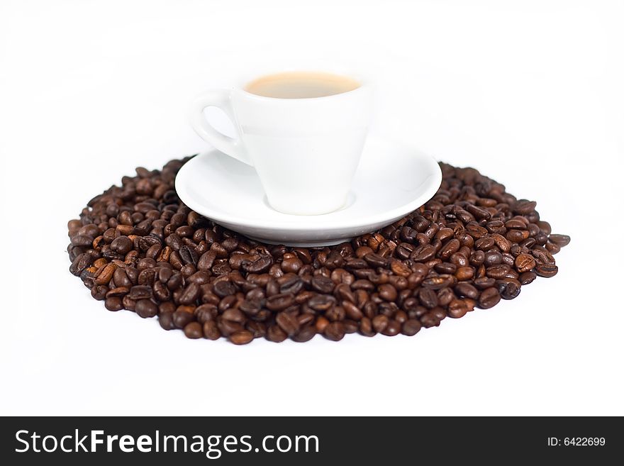 A cup of coffee on top of coffee beans isolated on white