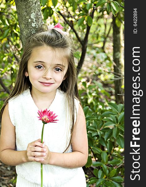 A beautiful girl dressed in white holding a pink flower. A beautiful girl dressed in white holding a pink flower.