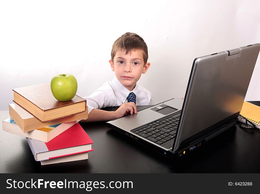 Little boy sitting at his desk in front of a laptop computer. Little boy sitting at his desk in front of a laptop computer
