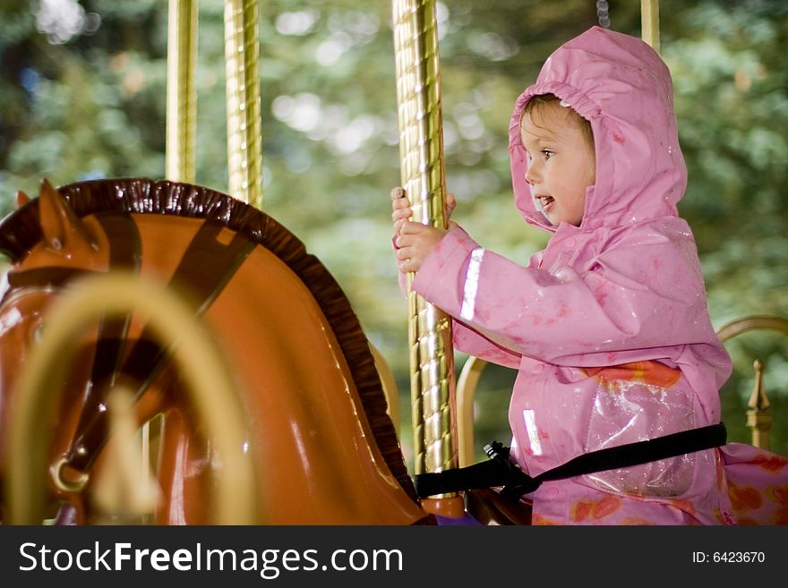 Little beauty girl on merry-go-round in the rain. Little beauty girl on merry-go-round in the rain
