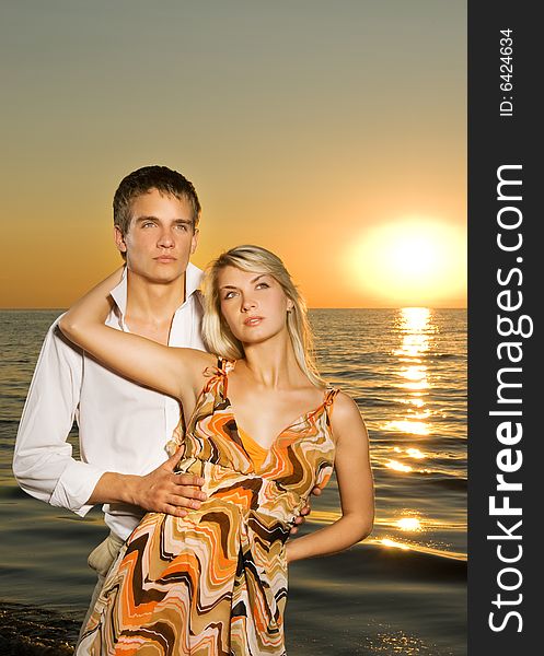 Young couple in love near the ocean at sunset