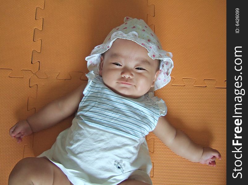 Pretty baby is smiling on a yellow mat