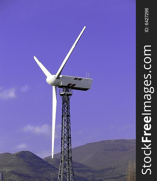View of wind turbine against blue sky and clouds.