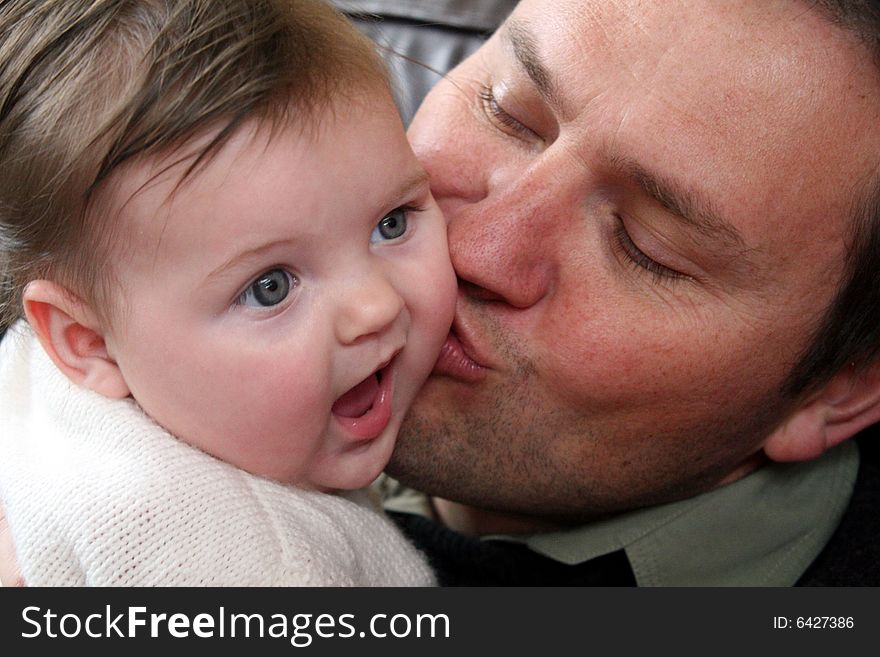 Baby girl receiving kisses from her dad. Baby girl receiving kisses from her dad