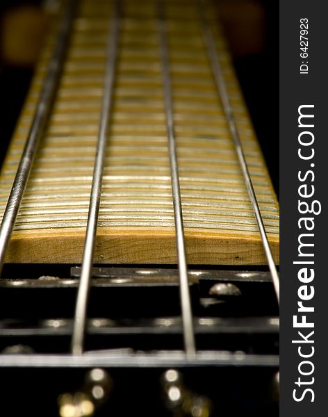 A closeup shot of a black four string bass guitar