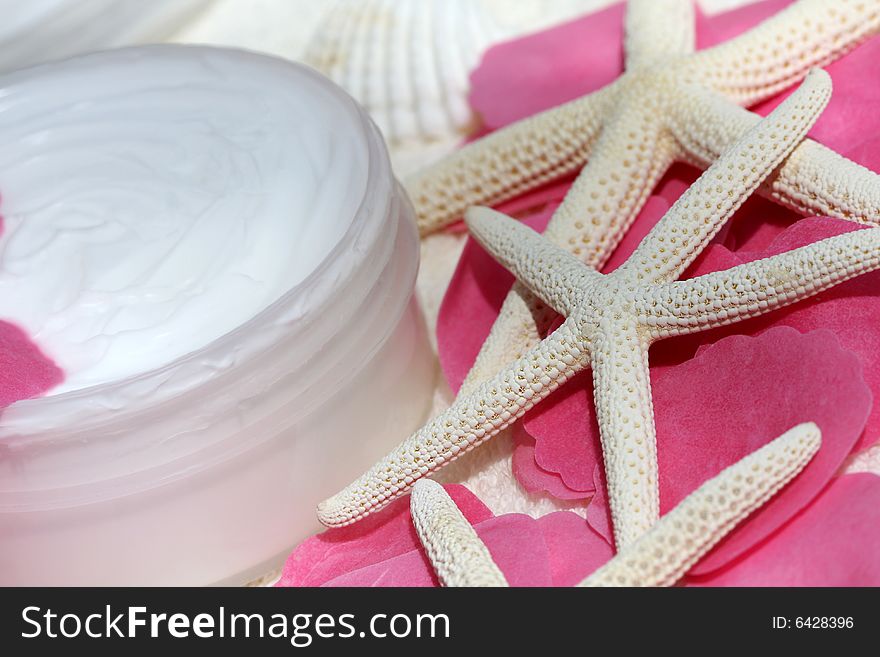 Body cream with soap rose petals and starfishes on white towel, closeup. Body cream with soap rose petals and starfishes on white towel, closeup