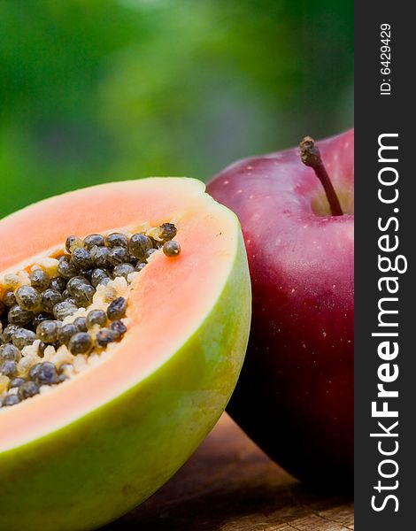 Close up of a half papaya and a red apple. Close up of a half papaya and a red apple