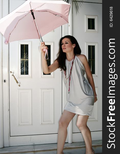 A beautiful young brunette woman holding a pink umbrella. A beautiful young brunette woman holding a pink umbrella
