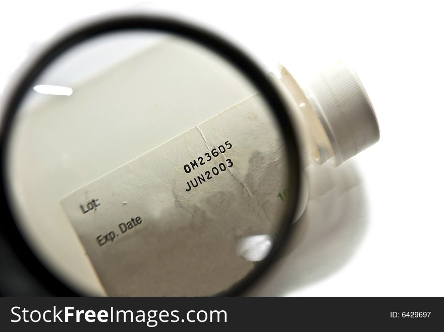 A magnifier on the expired date of an old prescription bottle. A magnifier on the expired date of an old prescription bottle.