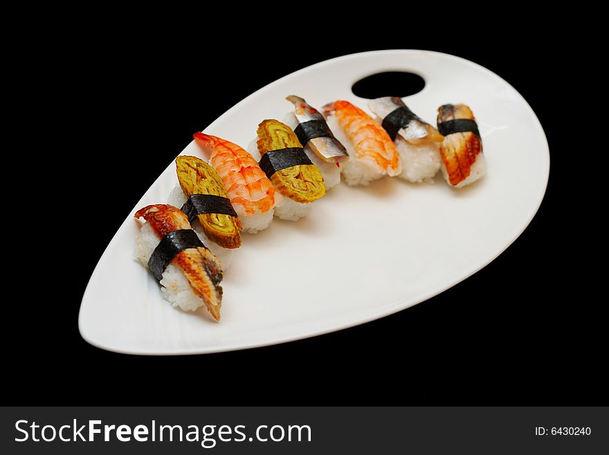 Set of different nigiris on a white plate isolated on black